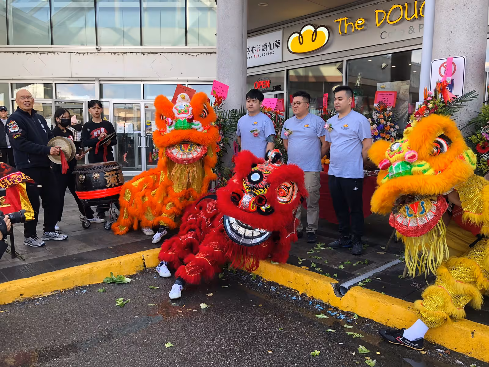 Lions performing at a store grand opening with the owners outside